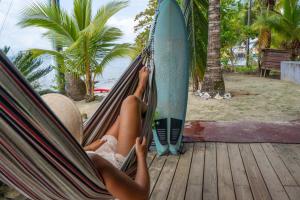 博卡斯德尔托罗Casa del Fuego - Caribbean Beachfront Magic!的躺在冲浪板旁的吊床上的女人