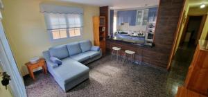 塔马达斯特VV EL OASIS的一间带蓝色沙发的客厅和一间厨房