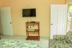 尼格瑞尔Charlie's Cottages的客厅设有壁挂式电视和桌子。