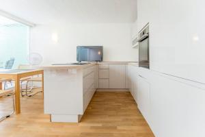 杜塞尔多夫Modernes, sonniges Appartement im Herzen von Düsseldorf的一间厨房,配有白色橱柜和台面上的电视