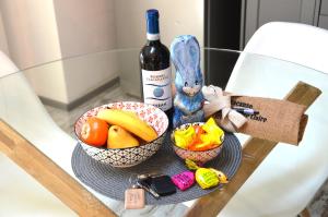 库尼奥La petite maison de Claire的一张玻璃桌,上面有两篮水果和一瓶葡萄酒