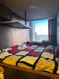 瓦迪穆萨Petra cabin Roof top hostel的窗户客房内的一张带五颜六色被子的床