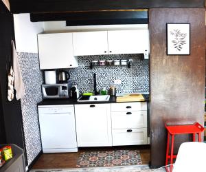 库尼奥La petite maison de Claire的厨房配有白色橱柜和红色凳子
