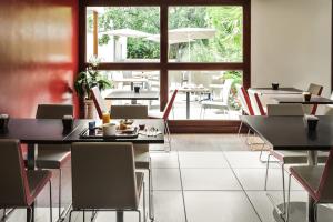 欧什宜必思奥赫酒店的餐厅设有桌椅和大窗户。
