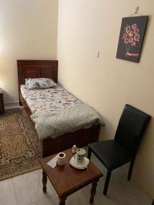 阿布扎比MBZ - Comfortable Room in Unique Flat的一间卧室配有一张床、一把椅子和一张桌子