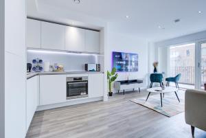伦敦Luxe Apartment by Excel的一间带白色橱柜的厨房和一间带桌子的客厅
