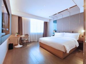 广州柏高酒店(广州南站番禺长隆店)的酒店客房设有一张大床和一张桌子。