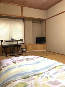 NosegawaMinshuku Kawarabi-so的一间卧室配有一张床、一张桌子、一张桌子和一台电视。