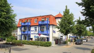 奥斯赛拜-屈隆斯博恩Hotel von Jutrzenka的蓝色和白色的建筑,带有橙色的屋顶