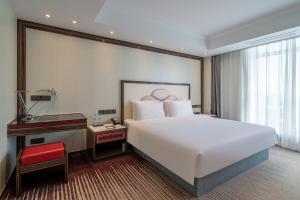 南京南京苏宁环球套房饭店的卧室配有一张白色大床和一张书桌