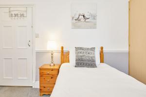 惠特比Apartment 1 - Khyber Lodge Apartments的一间卧室配有一张带白色床单和一盏灯的床。