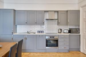惠特比Apartment 3, Khyber Lodge Apartments Whitby的厨房配有灰色的橱柜和木桌。