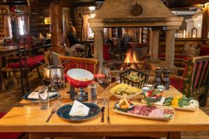 巴德加斯坦MONDI Schiefe Alm Gastein的餐桌、食品和酒杯以及壁炉