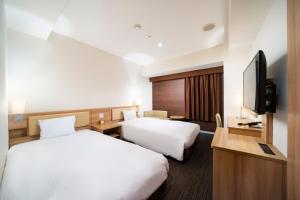 札幌KOKO HOTEL Sapporo Ekimae的酒店客房设有两张床和一台平面电视。