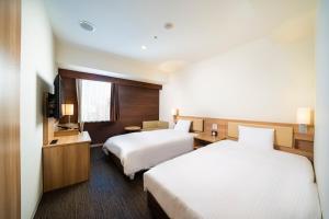 札幌KOKO HOTEL Sapporo Ekimae的酒店客房设有两张床和电视。