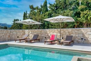 罗希姆诺La Serena Residence & Farm with Heated Pool的一个带两把椅子和两把遮阳伞的游泳池
