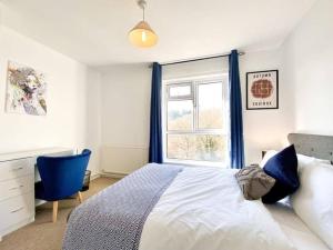 BatheastonScarlet House的一间卧室配有一张带蓝色椅子的床和窗户