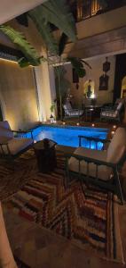 马拉喀什RIAD DAR NAOMI的一间带桌椅的客厅和一个游泳池