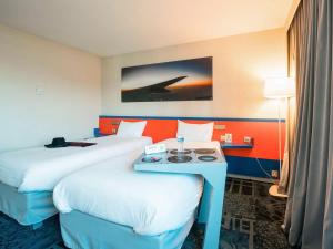 维特罗勒马赛机场宜必思尚品酒店的酒店客房设有两张床和一张桌子。