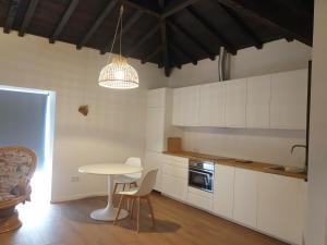 FontelasQuinta de Sobre a Fonte Charming Apartments的厨房配有白色橱柜和桌椅