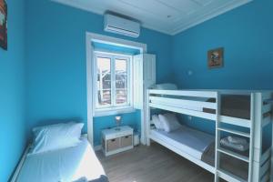 萨格里什国际冲浪学校&露营旅馆的蓝色的客房设有两张双层床和一扇窗户。