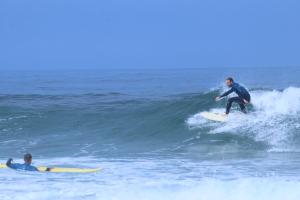 萨格里什国际冲浪学校&露营旅馆的两个在海浪冲浪板上挥手的人