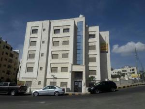 安曼Dair Ghbar 2-bedrooms unit的两辆车停在大楼前的建筑物
