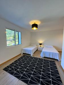 圣维森特The Passion Fruit House的卧室配有两张床,铺有黑白地毯。