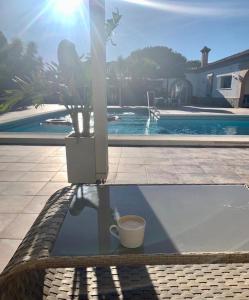 加的斯Villa Torrealta, 4000 m2, estancia mínima en verano 7 días de sábado a sábado的坐在游泳池畔的桌子上喝杯咖啡