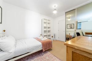伦敦Contemporary Top floor flat in Kentish Town的白色卧室配有床和书桌