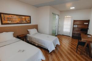 戈亚斯州上帕莱索Hotel Fazenda Bona Espero的酒店客房设有两张床和一张桌子。