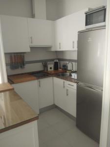 萨阿拉德洛斯阿图内斯Zaharaiso luz的厨房配有白色橱柜和不锈钢冰箱