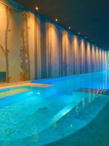 拉齐塞Natiia Relais - Adults Only的蓝色的水和窗帘的大型游泳池