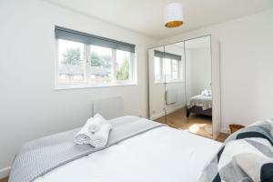 伦敦Sleek and Stylish 2BD Home with a Garden Anerley的白色卧室配有床和镜子