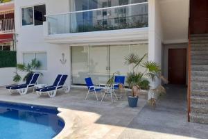 阿卡普尔科Hermoso Departamento Nuevo的一座带游泳池和蓝色椅子的房子