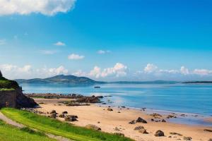 MuffArdmore Cottage - Failte Ireland Quality Assured的阳光明媚的日子里,海滩上拥有岩石和海洋
