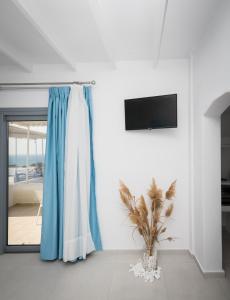 ProvatasSarantis Suites & Apartments的白色的房间,有蓝色窗帘和植物