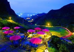 九份金瓜石艺栈景观度假别墅的一组桌子,晚上有粉红色的伞