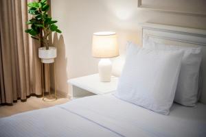 康斯坦察Apartament Zafi Lakeview的一张带白色枕头的床和一张带台灯的桌子