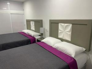 马萨特兰Posada 53的紫白色客房的两张床