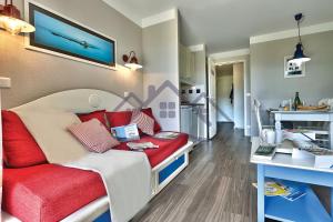 吉尔维内克LocaLise au Guilvinec - B5 - Plain-pied avec piscine et jardin - Tout à pied, plage, port, centre, commerces, marché - Wifi inclus - Linge de lit inclus - Animaux bienvenus的小房间设有一张红色沙发的床