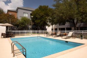 圆石城Courtyard by Marriott- Austin Round Rock的一座带桌椅的游泳池以及一座建筑