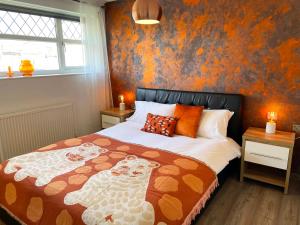 凯特林Bright, Airy & Beautifully Decorated 3 Bedroom Home的一间卧室配有一张橙色墙壁的床