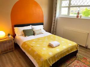 凯特林Bright, Airy & Beautifully Decorated 3 Bedroom Home的一间卧室配有一张带橙色床头板的大床