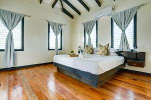 伯利兹城Shaka Caye All inclusive Resort的卧室配有一张大床、木地板和窗户。