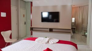 AcailandiaGênova Palace Hotel的卧室配有一张床铺,墙上配有电视