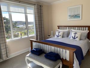 CarlowayTigh-na-Greine的一间卧室配有一张带蓝色枕头的床和一扇窗户。