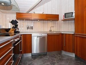 森讷比8 person holiday home in Juelsminde的厨房配有木制橱柜和不锈钢洗碗机。