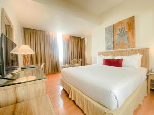 杜迈杜迈祖里格兰德酒店的卧室配有一张白色大床和电视。