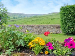 Rosedale Abbey科比伍德乡村别墅的一座花园,花园内种有五颜六色的鲜花,设有石墙
